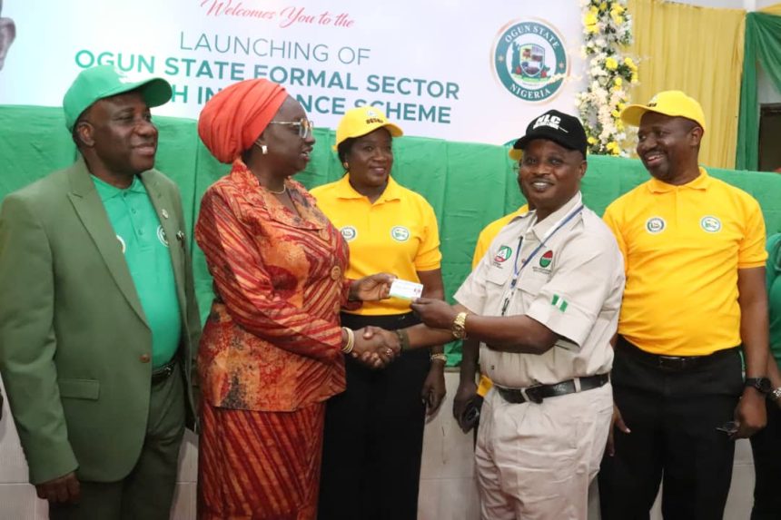 Engr. Noimot Salako-Oyedele (2nd left) presenting a Health Insurance Card to the Chairman, NLC, Comrade Ademola Benco (2nd right) during the official launch of the State Formal Sector Health Insurance Scheme in