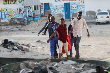 People carry the dead body of an unidentified woman killed in an explosion