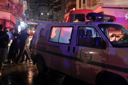 People stand near rescue vehicles at the site of an Israeli air strike