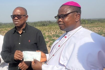 Peter Obi (left) presenting a cheque of N20m to the Auxiliary Bishop of the Catholic Diocese of Enugu, Most Rev. Dr. Ernest Obodo 